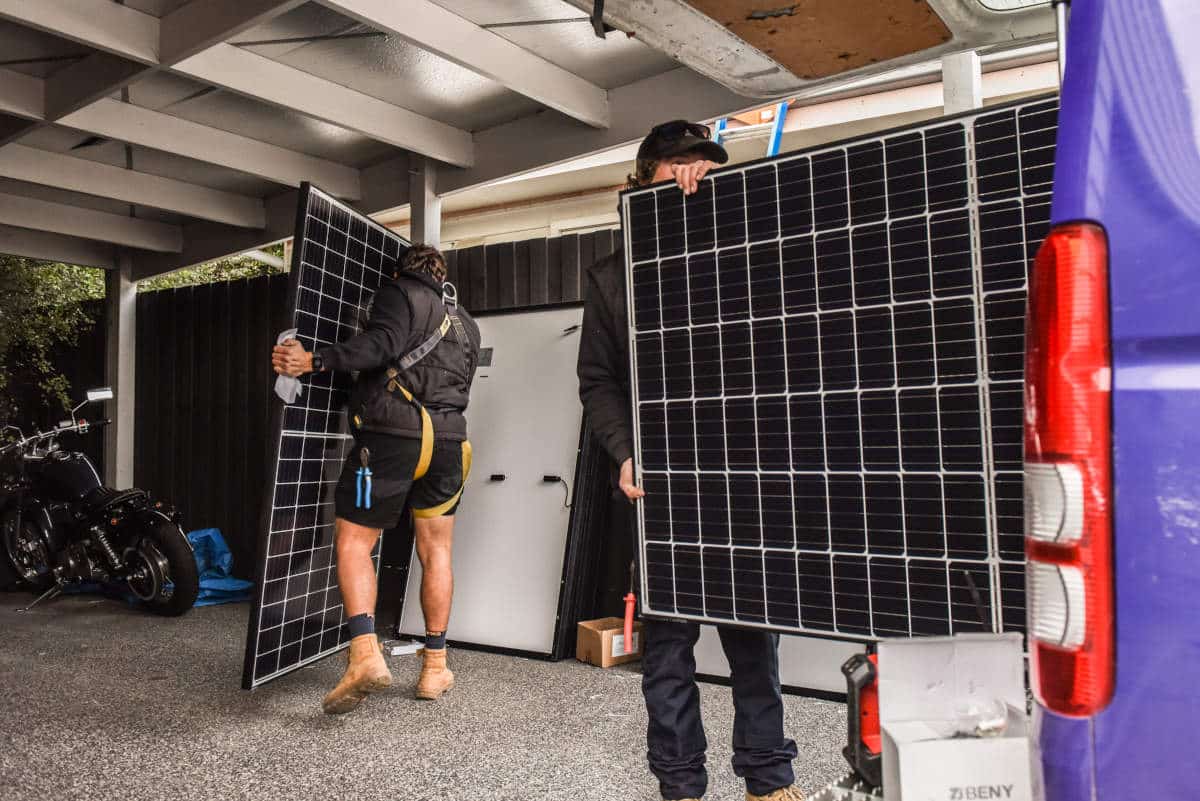 Erg Energy electricians carrying solar panels from the work van