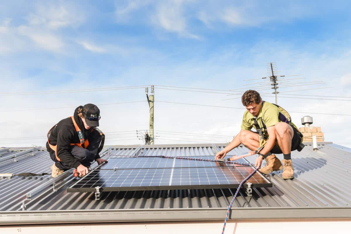 Two Erg Energy electricians fitting a solar panel on a tin roof